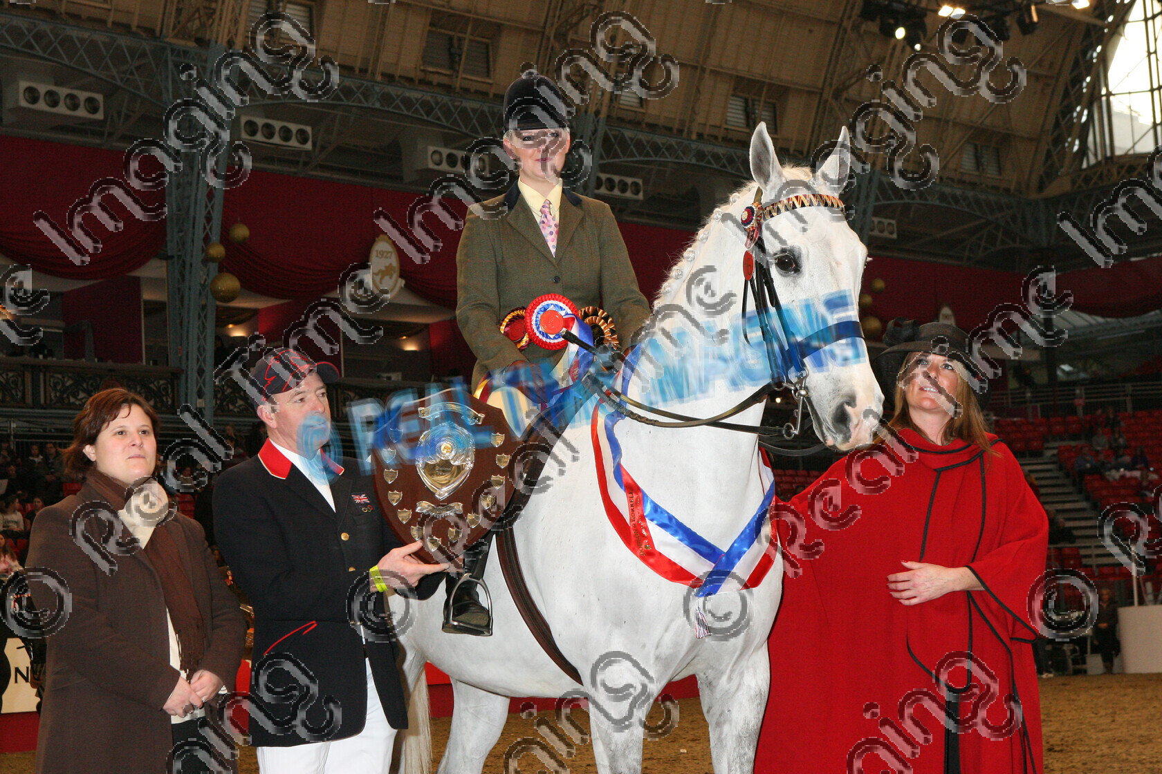S07-73-02-130 
 Keywords: Friday, 21 December, 2007, The London International Horse Show, Olympia, UK, The Veteran Horse Society, Supreme, Championship, indoors, view landscape, 189, BOWLANDS DIPLOMAT, 1st first, Champion, winner win won, `Rider: , Gill Bayley-Machin, 16 Years Old, grey gray, white, Rosette, sash, presentation, stand, plaque, trophy, 'Presented By: , brow band, Rebecca Ingram (Dodson & Horrell), John Whittaker, Julianne Aston (VHS Founder)