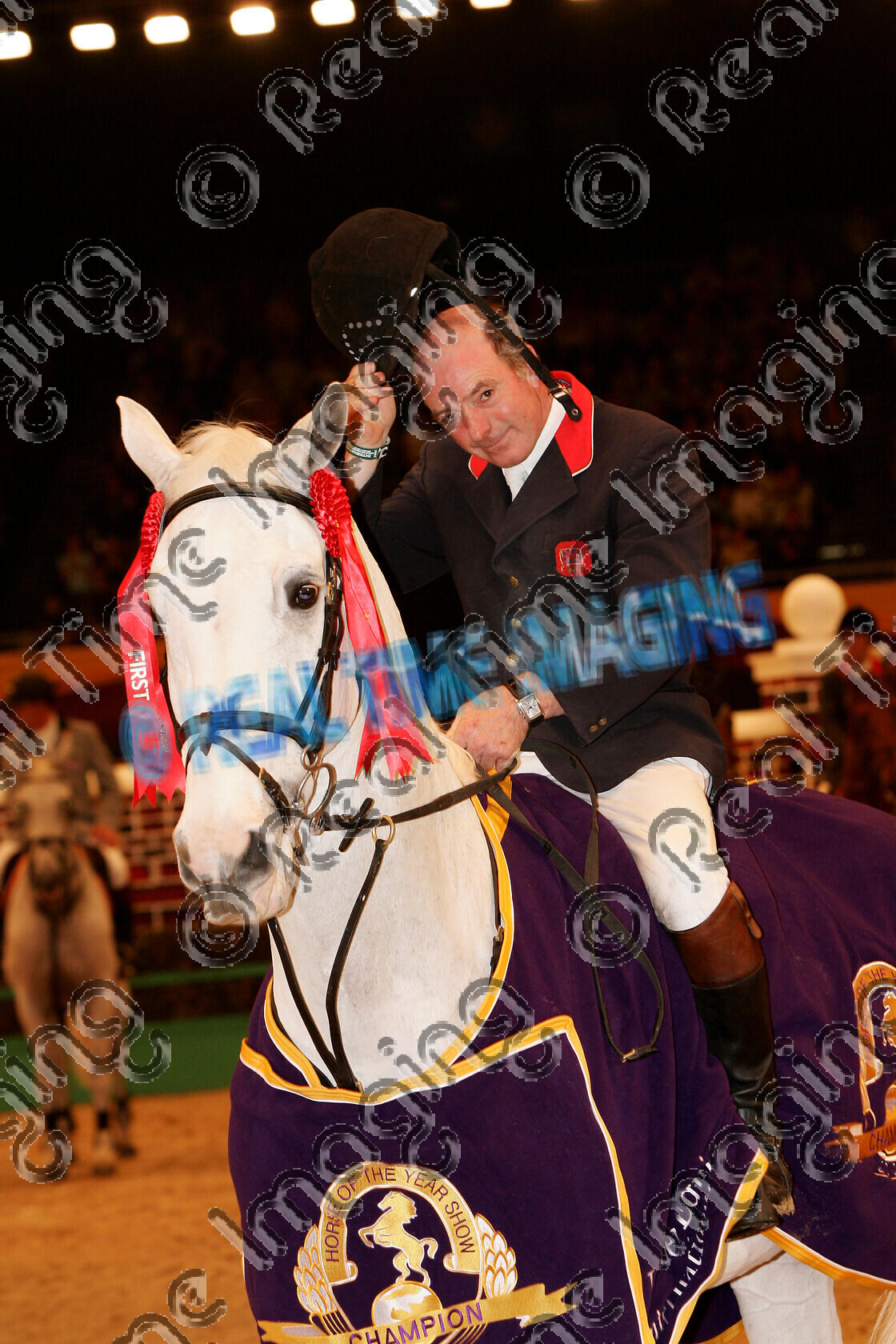 S05-67-12-076 
 HOYS 2005: The Horse Of The Year Show Puissance Winner 
 Keywords: horse of the year show 2005 05 hoys saturday 15 10 october showjumping showjumper 23 Puissance Winner 2 Lactic John Whitaker grey gray gelding standing presentation rug trophy rosette